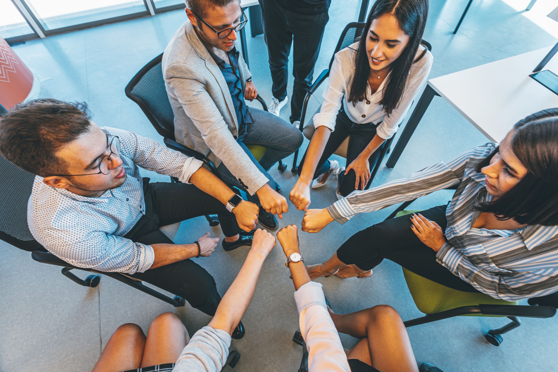 A team of colleagues joining their hands together in unity in a creative luxury office
